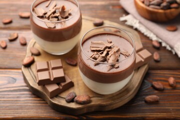 Delicious panna cotta with chocolate and cocoa beans on wooden table, closeup