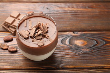 Delicious panna cotta with chocolate on wooden table, closeup. Space for text