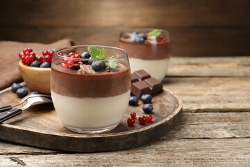 Delicious panna cotta with chocolate, berries and mint on wooden table, closeup. Space for text