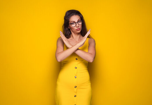 Limit. Woman gesturing stop or x sign with her arms, refuses or reject something, girl crossing her hands, isolated on yellow background.