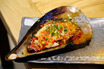 Grilled scallop topped with garlic, chili, and chopped green onions