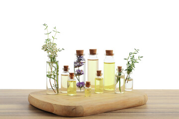 Bottles of essential oils and different herbs on wooden table against white background