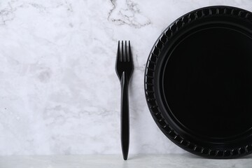 Disposable plastic plate and fork on light grey table, space for text