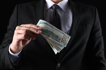 Man with dollar bills on black background, closeup