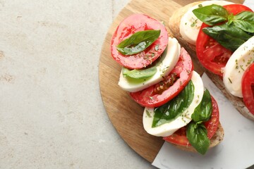 Delicious sandwiches with mozzarella cheese, tomatoes and basil on light grey textured table, top view. Space for text