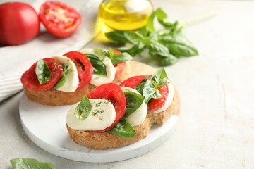 Delicious sandwiches with mozzarella cheese, tomatoes and basil on light grey table, closeup