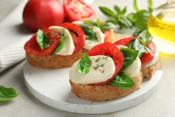 Delicious sandwiches with mozzarella cheese, tomatoes and basil on light grey table, closeup