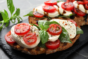 Delicious sandwiches with mozzarella cheese, tomatoes and basil on table, closeup