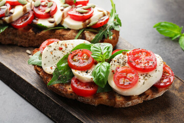 Delicious sandwiches with mozzarella cheese and tomatoes on grey table, closeup