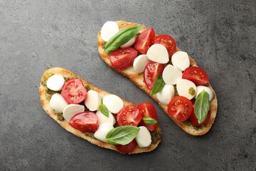 Delicious sandwiches with mozzarella cheese, tomatoes and basil on grey textured table, flat lay