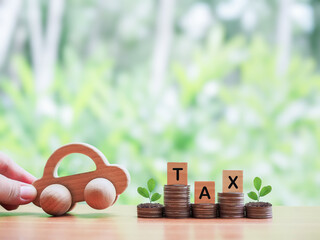Wooden toy car, Wooden blocks with the word TAX and plants growing up on stack of coins. The...