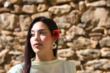 A beautiful Spanish teenager with long dark hair and a delicate, beautiful red poppy in her hair...