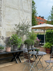 Cozy cafe garden with plants in Copenhagen city park in Denmark. Table with chairs under open sky...