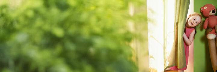 Child Playing Peekaboo by Curtain Wide Banner with Copy Space