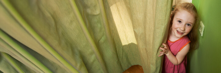 Smiling Child Behind Curtains Wide Banner with Copy Space