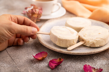 Сhocolate Ice cream in white glaze, cup of coffee, with hand on brown concrete, side view, close up, selective focus