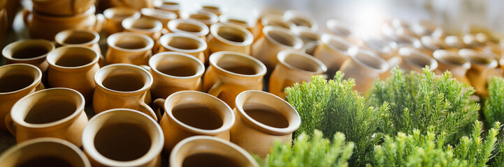 Rows of Clay Mugs with Greenery - Wide Banner
