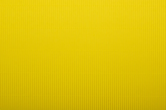 A vibrant yellow corrugated surface with a ribbed texture, perfect for use as an abstract background.