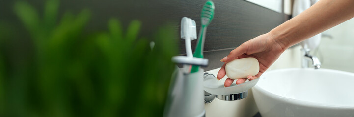 Hand Holding Soap in Bathroom Wide Banner with Copy Space