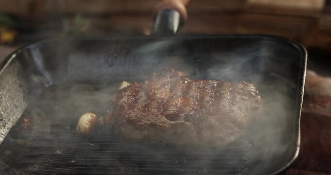 Beef steak on fire coals on frying pan grill in flame of smoke. Barbecue pork steak meat on grill. Roasting beef steak in burning charcoals fire on bbq grill. Beef steak grilling. Barbecue meat grill
