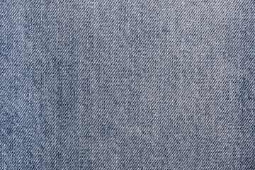 Close-up of stonewashed denim jeans fabric background backdrop. Traditional fashion garment fabric concept.