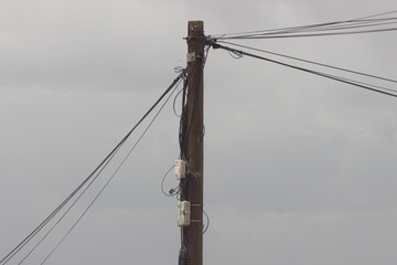 A tall wooden utility pole set against a backdrop of a cloudy sky