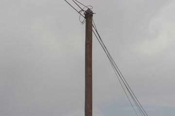 A tall wooden utility pole set against a backdrop of a cloudy sky