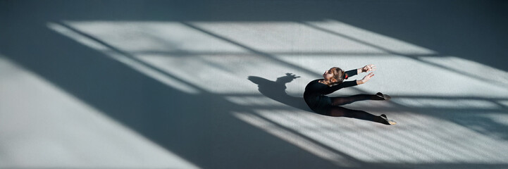 Fototapeta premium Dancer on Studio Floor with Shadows, Wide Banner