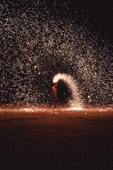 Fire dancer performing with sparks at night on the beach