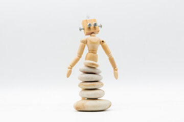 Muñeco de madera con cabeza de robot, con piedras apiladas delante, a modo de falda surrealista