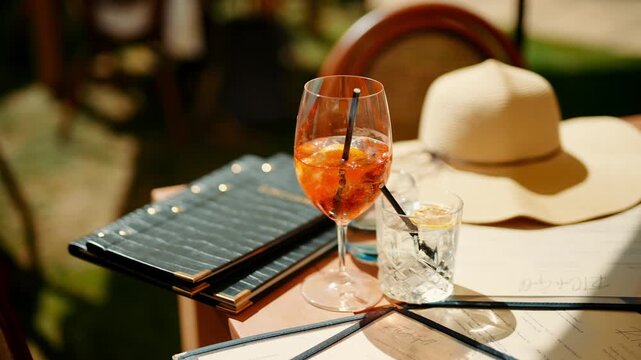 A glass of wine sits on a table next to a menu and a straw. The scene is set in a restaurant or bar, and the atmosphere is relaxed and casual