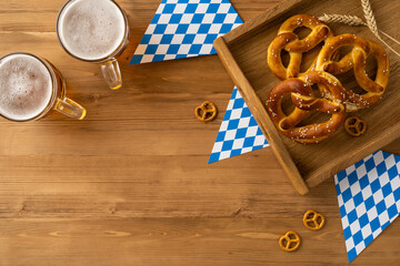 Celebrate Oktoberfest with mugs of beer and salty pretzels on a rustic top view wooden table