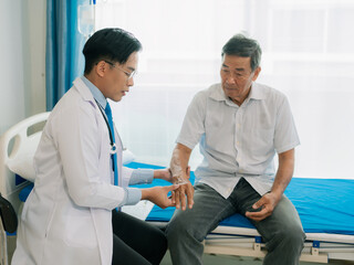 Obraz premium A skilled male physical therapist examines an elderly male patient lying on a bed, checking his muscle strength in a hospital examination room.