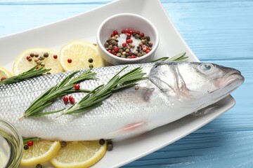 Fresh raw seabass with spices on blue wooden table, closeup. Fish and seafood delicacies