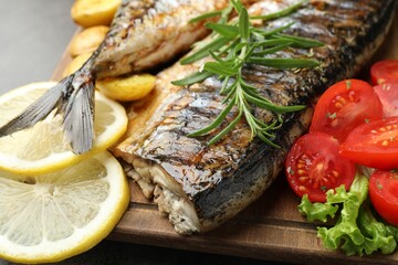 Tasty roasted mackerels with spices and vegetables on table, closeup. Homemade seafood dish