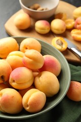 Fresh ripe apricots in bowl, kernels and knife on table, closeup