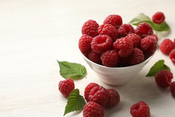 Tasty fresh ripe raspberries and leaves on white wooden table, closeup. Space for text