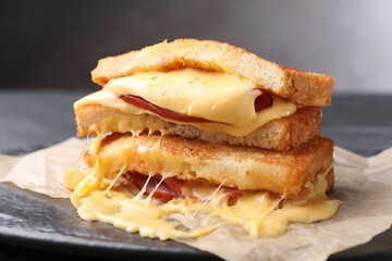 Tasty sandwiches with melted cheese and ham on table, closeup