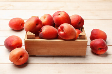 Fresh ripe apricots in crate on light wooden table, closeup