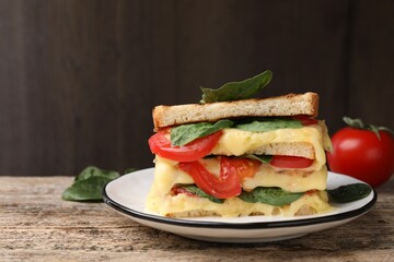 Delicious sandwiches with melted cheese, spinach and tomatoes on wooden table, space for text