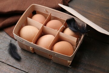 Raw chicken eggs in egg tray on wooden table, closeup