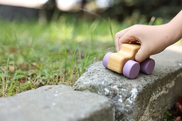Little boy playing with toy car outdoors, closeup. Space for text