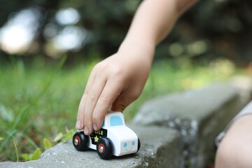 Little boy playing with toy car outdoors, closeup