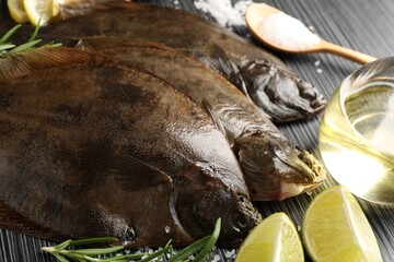 Fresh flounder fish, salt and products on black wooden table, closeup. Raw seafood