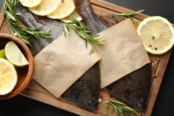 Fresh raw flounder fish and spices on black wooden table, top view. Seafood