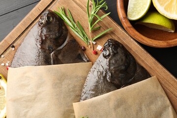 Fresh raw flounder fish and spices on black wooden table, top view. Seafood