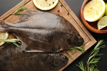 Fresh raw flounder fish and spices on black wooden table, flat lay. Seafood