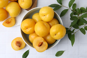 Ripe yellow cherry plums on white tiled table, flat lay