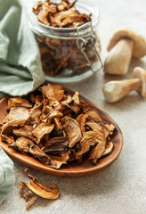 Dried mushrooms on wooden plate with fresh mushrooms and jar