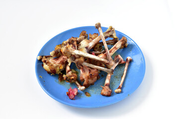 On a blue plate there is a pile of bones from an eaten chicken.